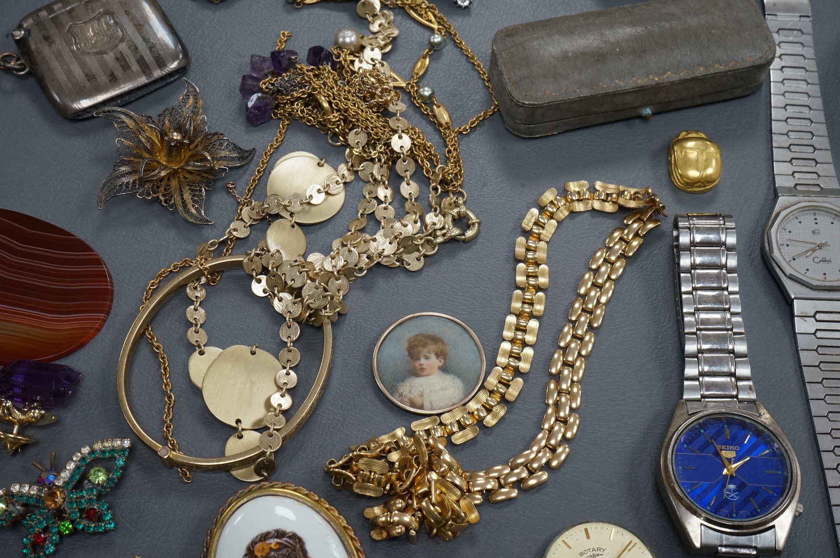 A quantity of assorted costume jewellery and other items including wrist watches, watch movements and a silver vesta case.